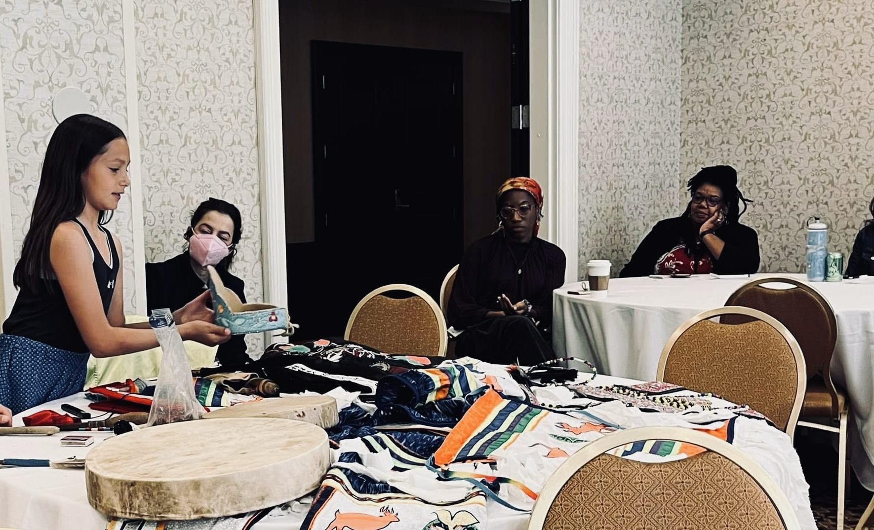 Kya sharing teachings about regalia and cultural items at a gathering.